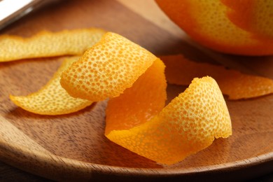 Photo of Fresh orange peel and fruit on wooden table, closeup