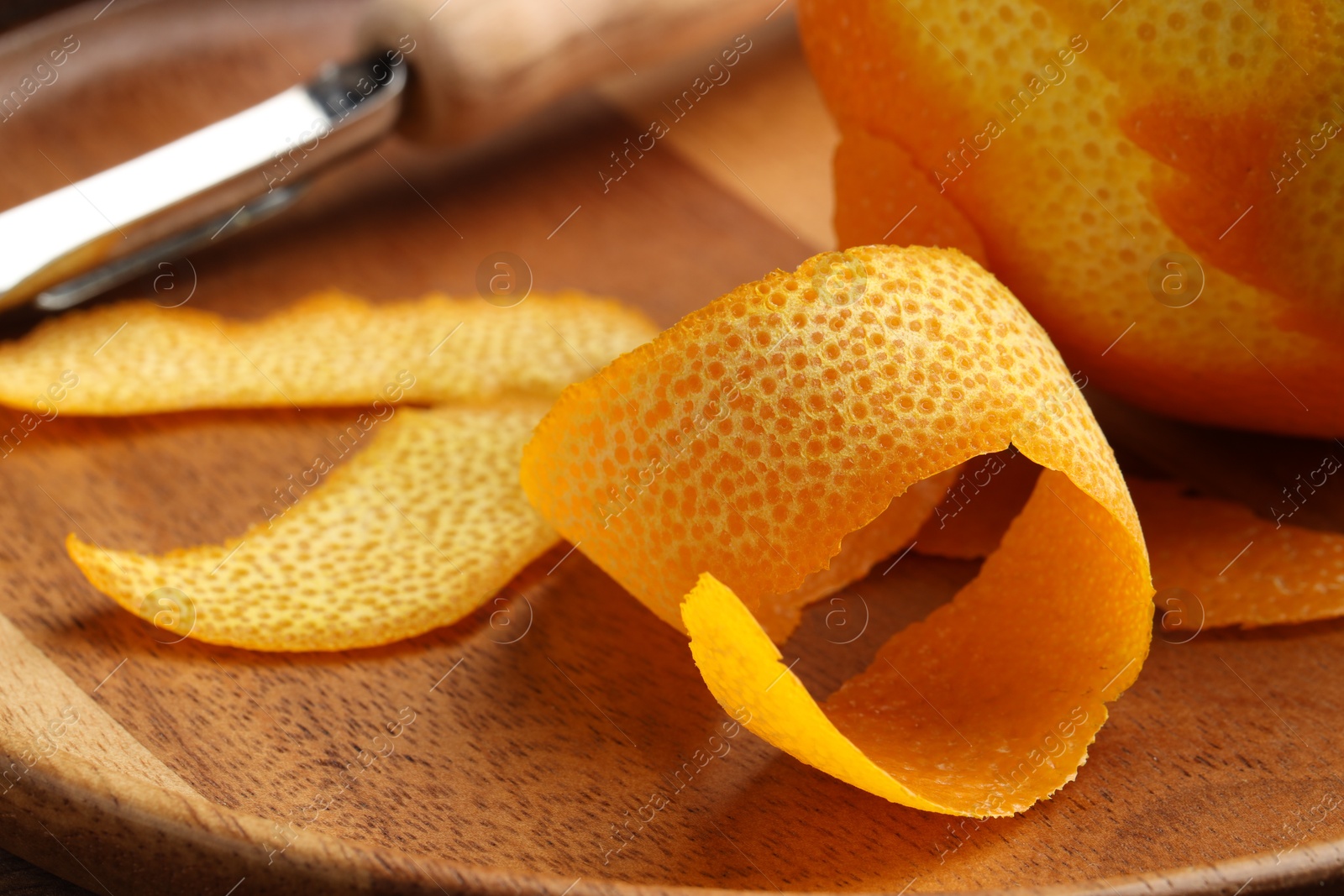 Photo of Fresh orange peel, channel knife and fruit on wooden table, closeup