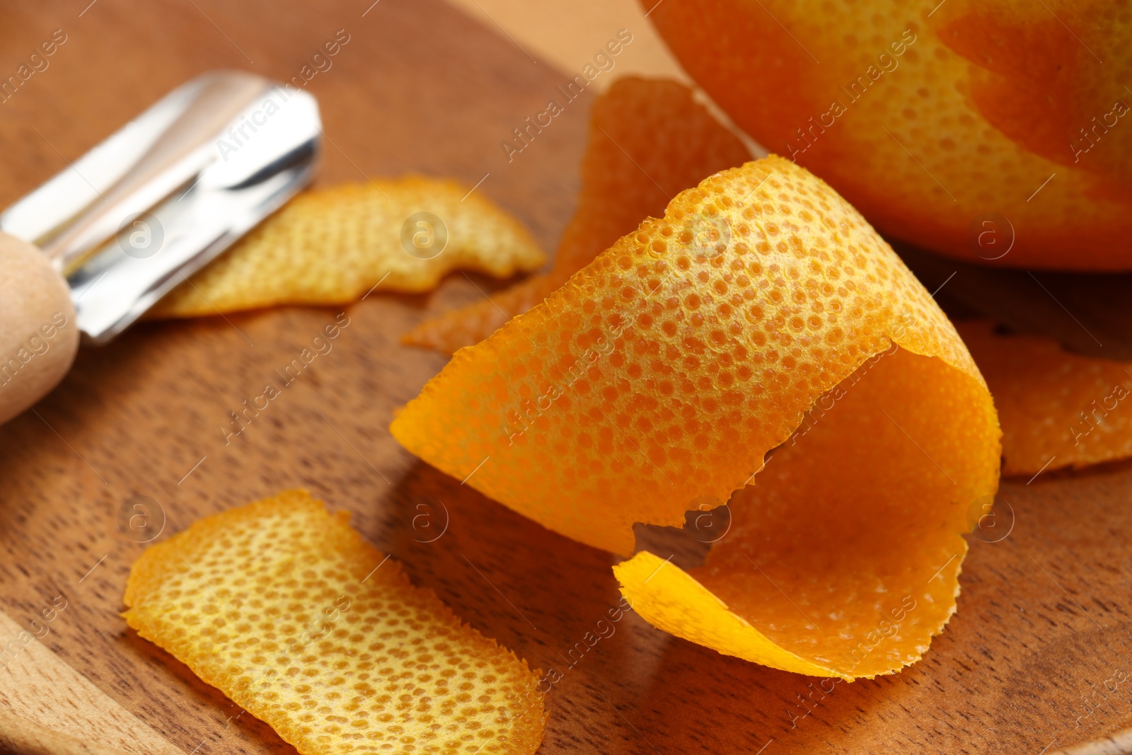 Photo of Fresh orange peel, channel knife and fruit on wooden table, closeup