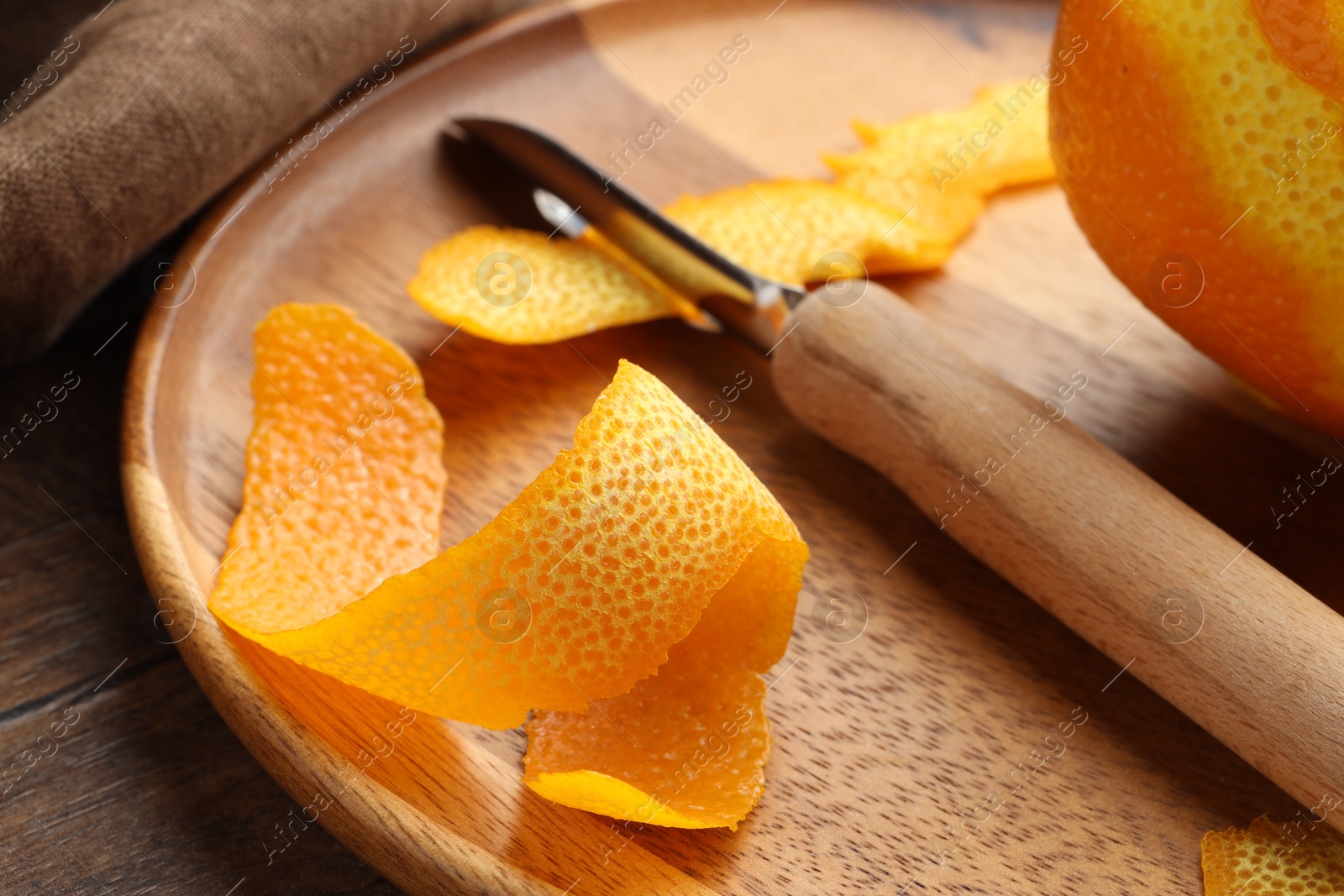 Photo of Fresh orange peel, channel knife and fruit on wooden table, closeup