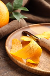 Photo of Fresh orange peel and channel knife on wooden table, closeup