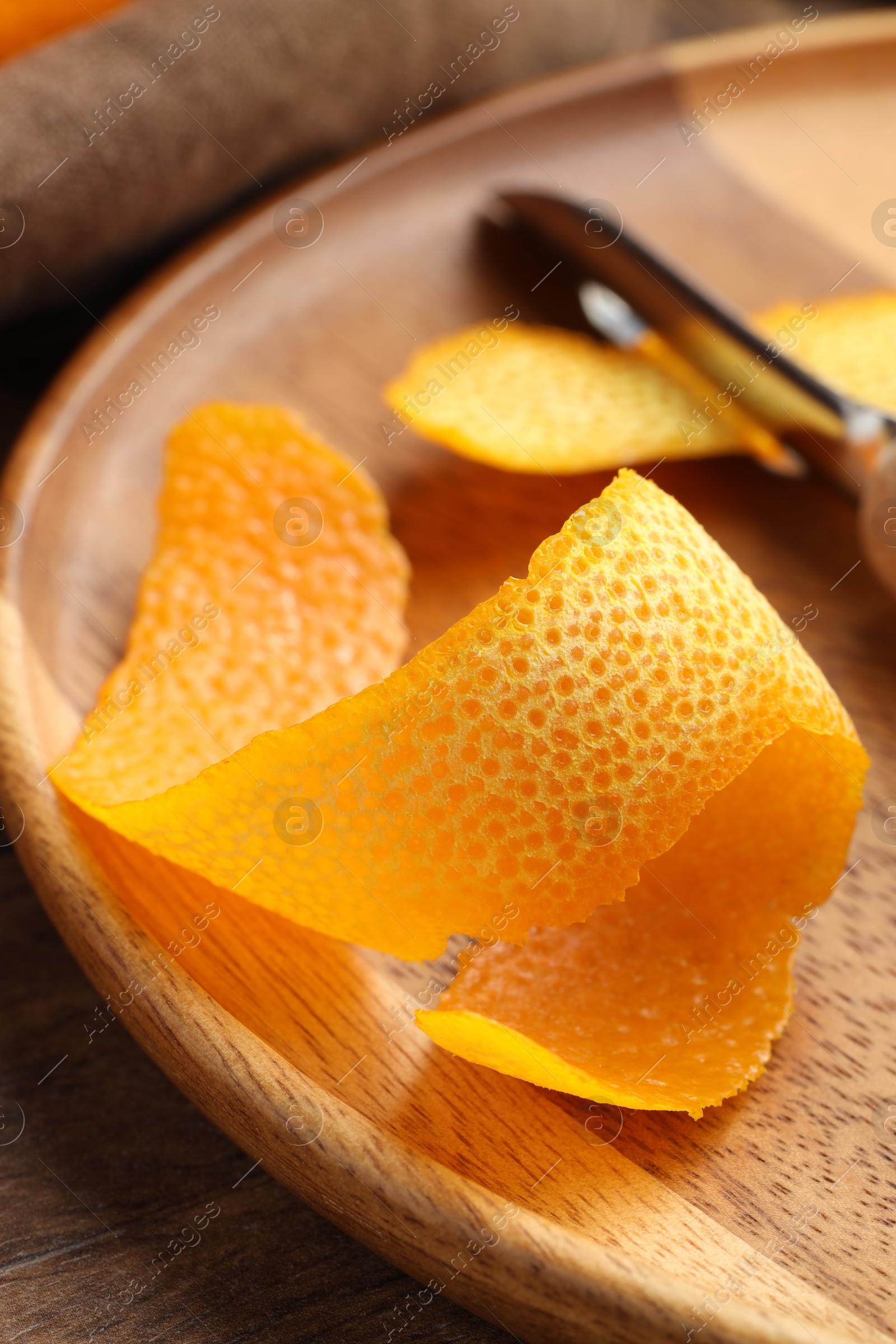 Photo of Fresh orange peel and channel knife on wooden table, closeup