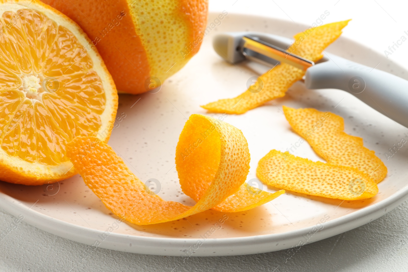 Photo of Fresh orange peel, fruit and peeler on light table, closeup