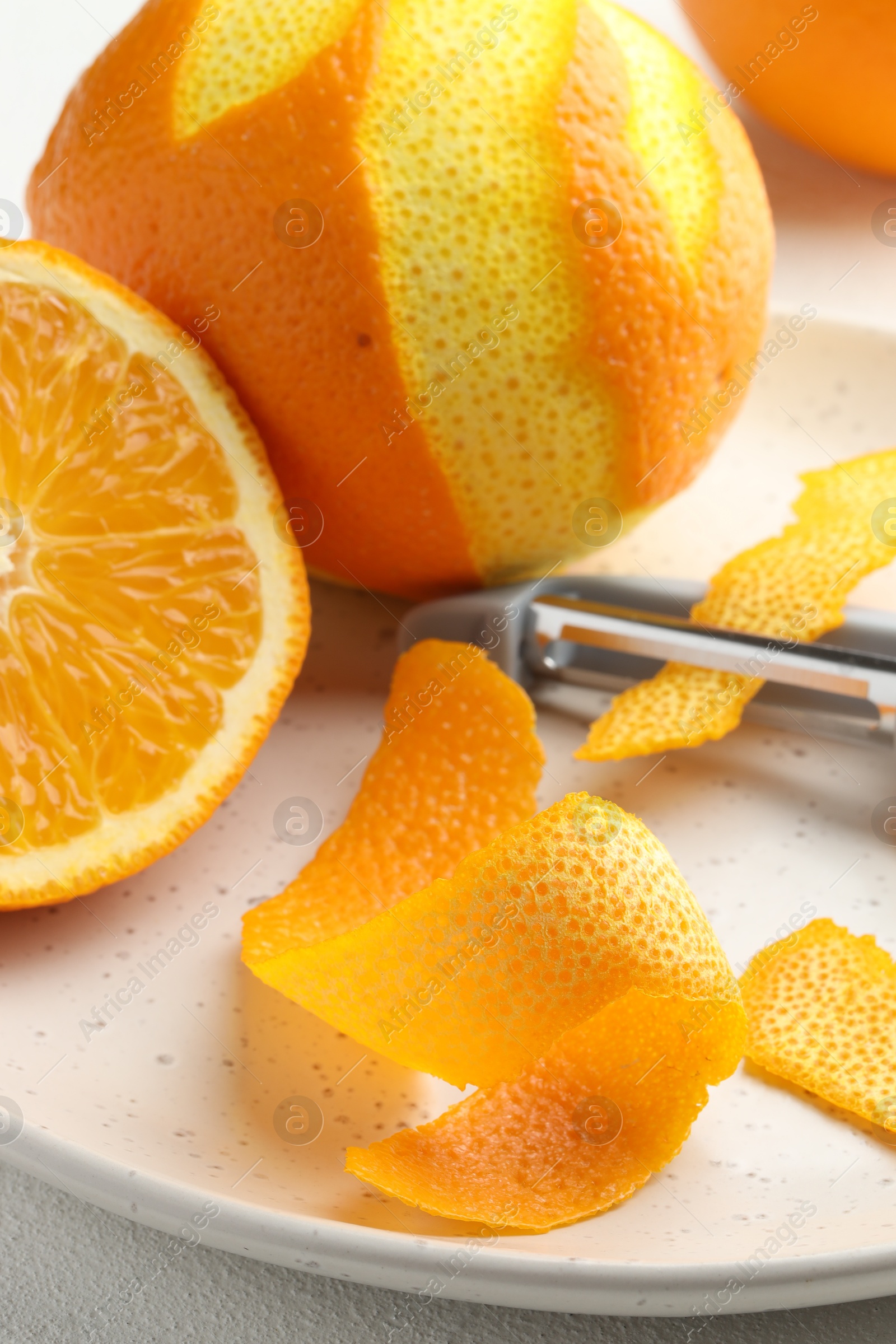 Photo of Fresh orange peel, fruit and peeler on light table, closeup