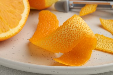 Photo of Fresh orange peel and fruit on light table, closeup