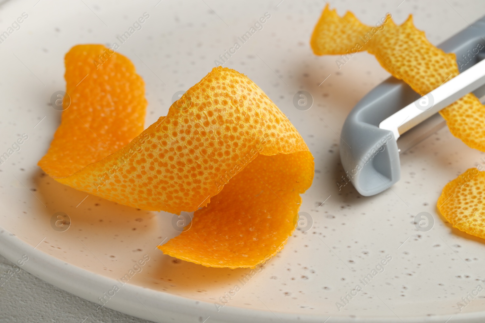 Photo of Fresh orange peel and peeler on table, closeup