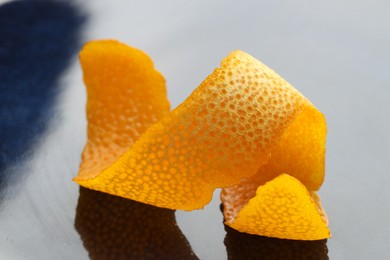 Fresh orange peel on dark table, closeup