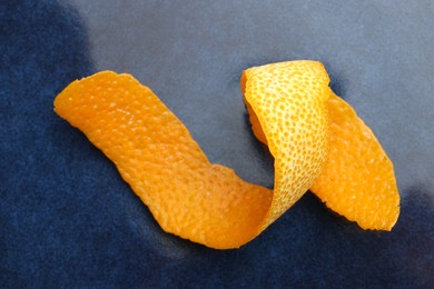 Photo of Fresh orange peel on blue table, closeup