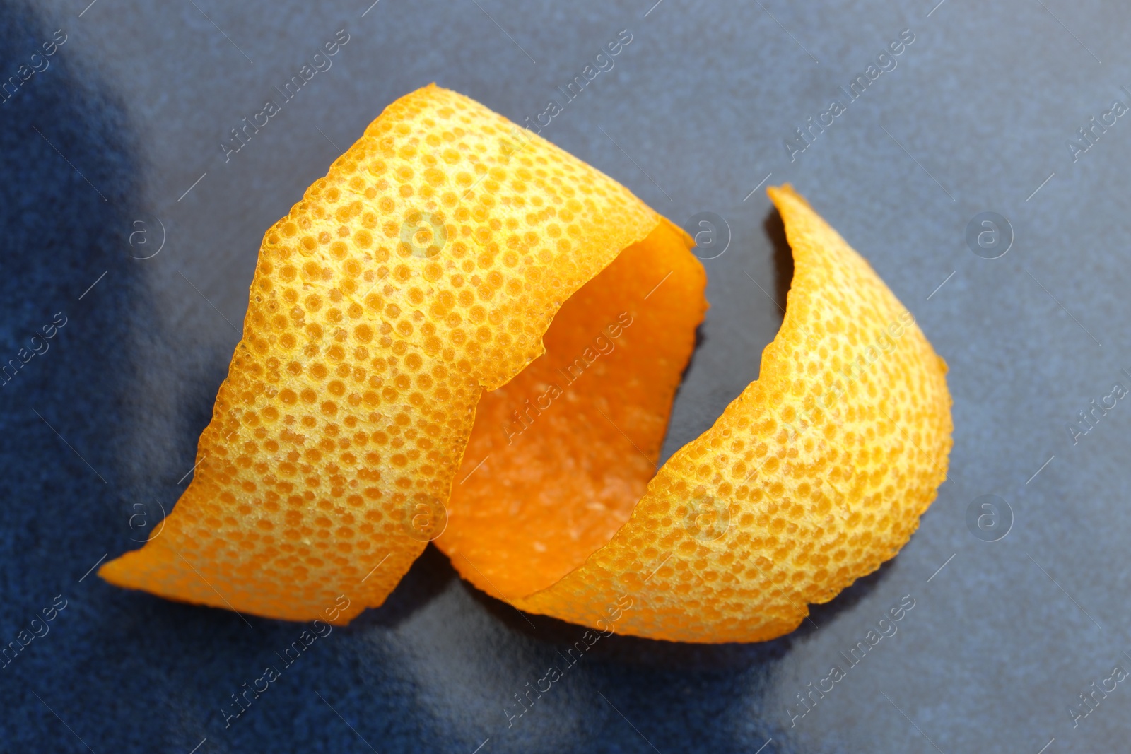 Photo of Fresh orange peel on blue table, closeup