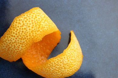 Photo of Fresh orange peel on blue table, closeup