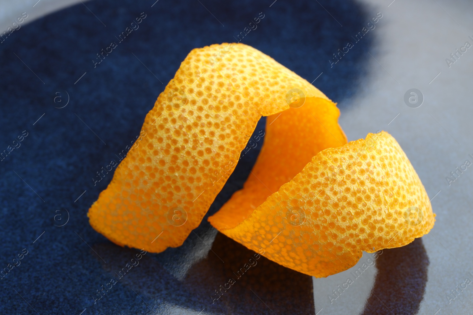 Photo of Fresh orange peel on blue table, closeup