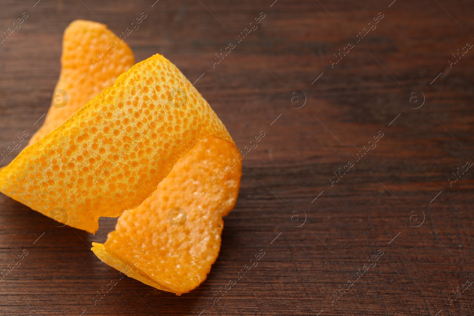 Photo of Fresh orange peel on wooden table, closeup. Space for text