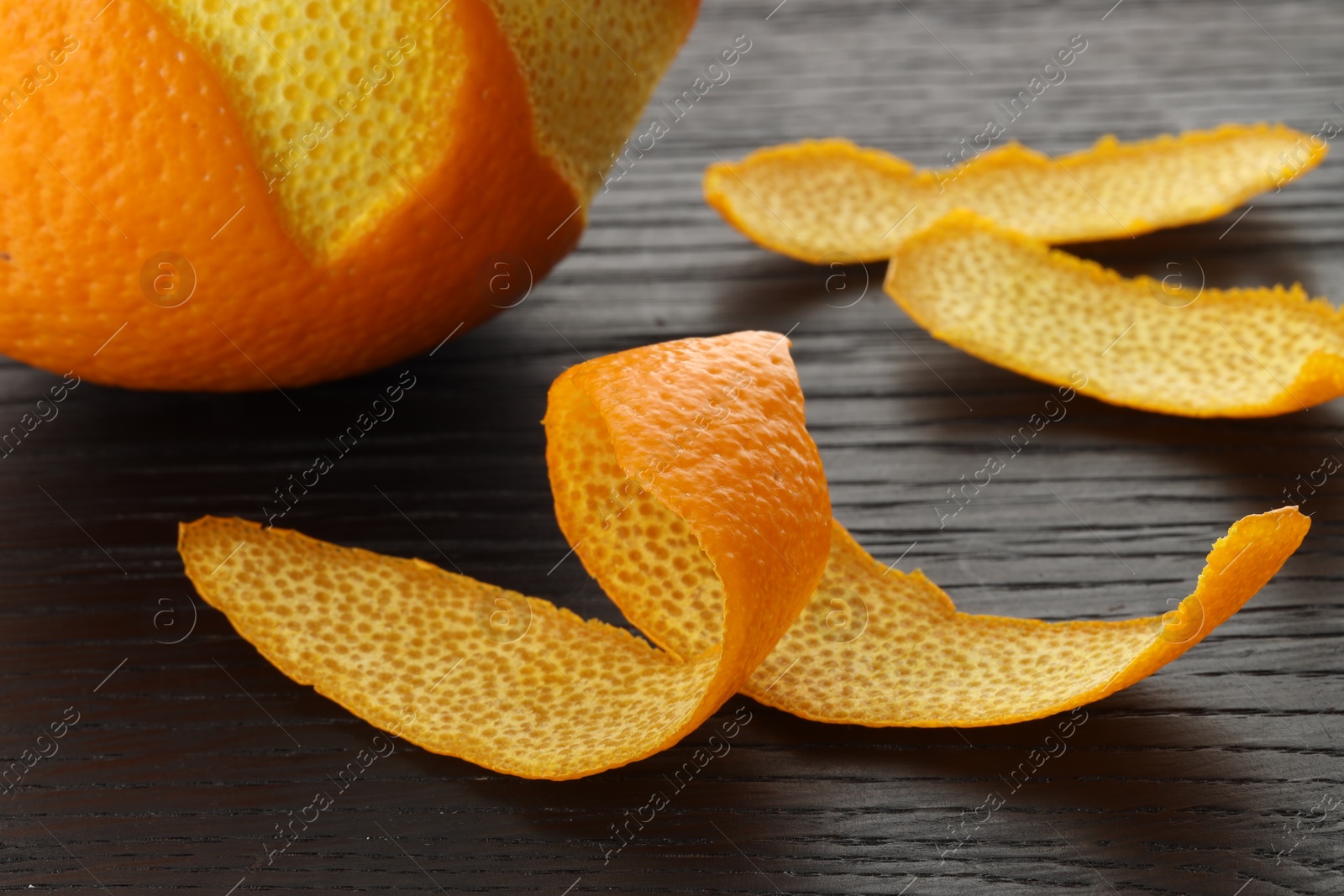 Photo of Fresh orange peels and fruit on wooden table, closeup