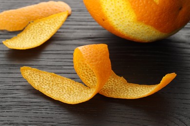 Photo of Fresh orange peels and fruit on wooden table, closeup