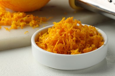 Photo of Fresh orange zest, grater and fruit on light table, closeup