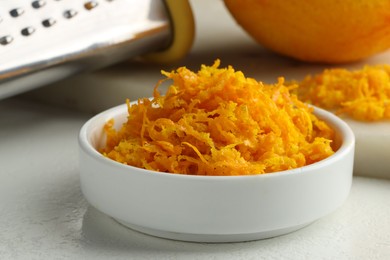 Photo of Fresh orange zest, grater and fruit on light table, closeup