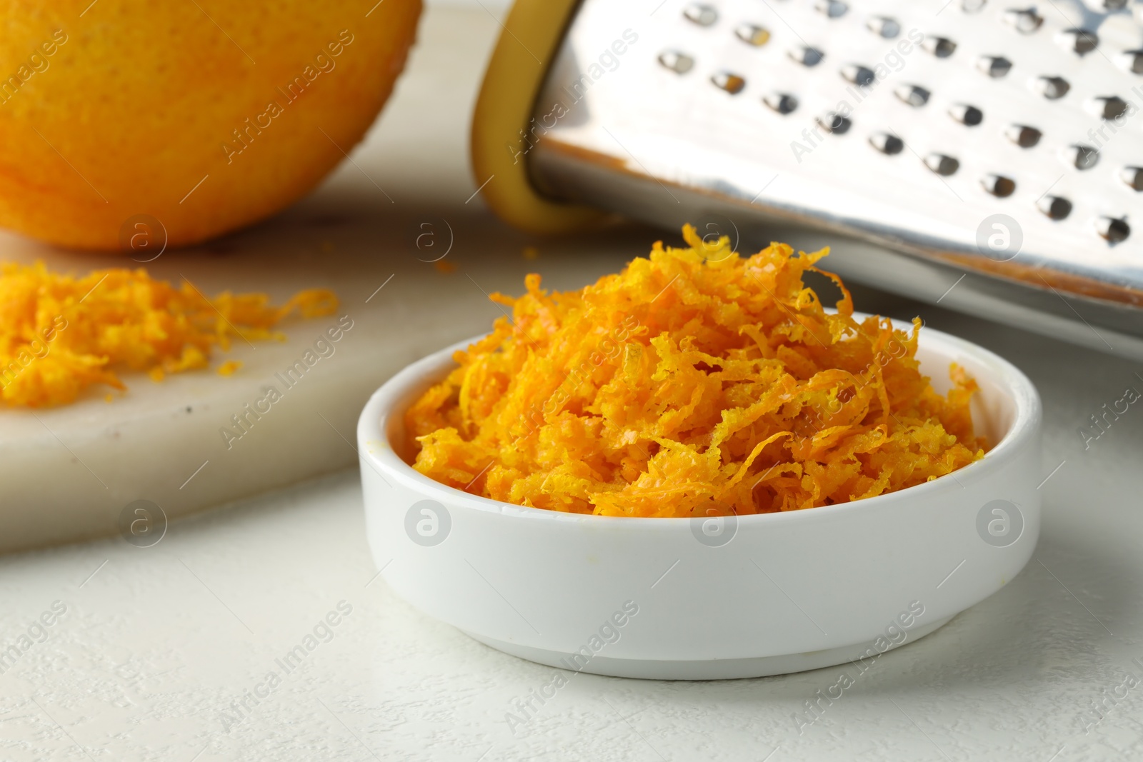 Photo of Fresh orange zest, grater and fruit on light table, closeup