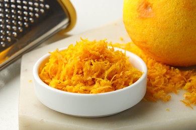 Photo of Fresh orange zest, grater and fruit on light table, closeup