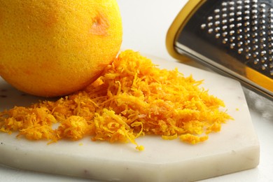 Photo of Fresh orange zest, grater and fruit on light table, closeup