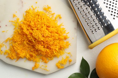 Fresh orange zest, grater and fruit on light table, flat lay