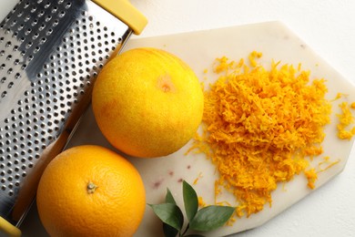 Photo of Fresh orange zest, grater and fruits on light table, flat lay