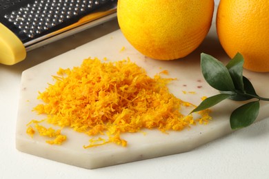 Photo of Fresh orange zest, grater and fruits on light table, closeup