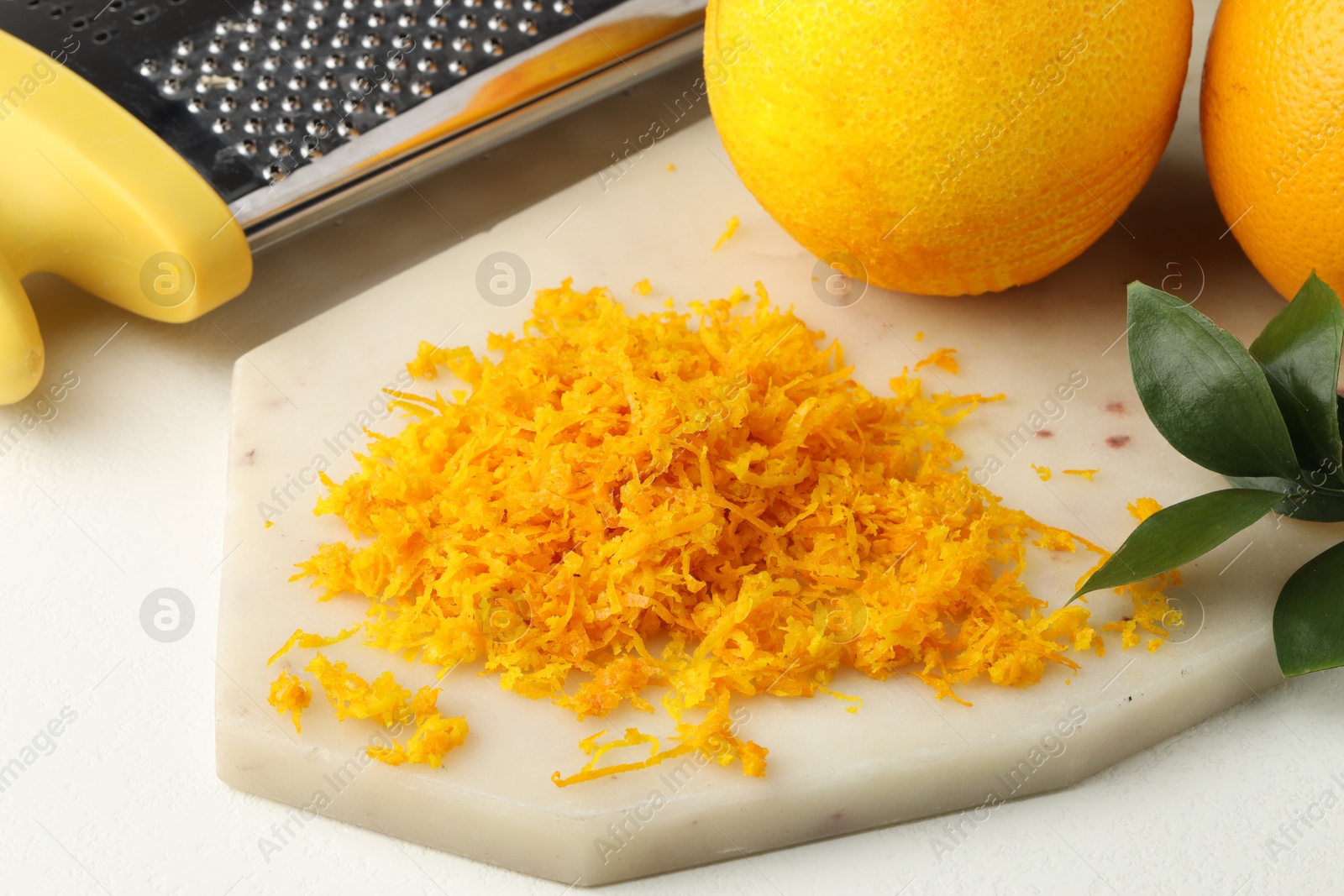 Photo of Fresh orange zest, grater and fruits on light table, closeup