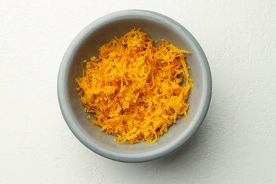 Photo of Fresh orange zest in bowl on light table, top view