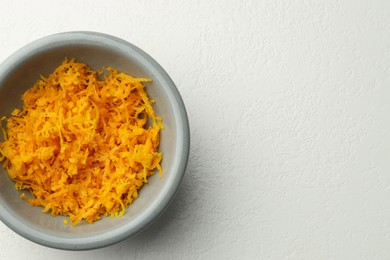 Photo of Fresh orange zest in bowl on light table, top view. Space for text