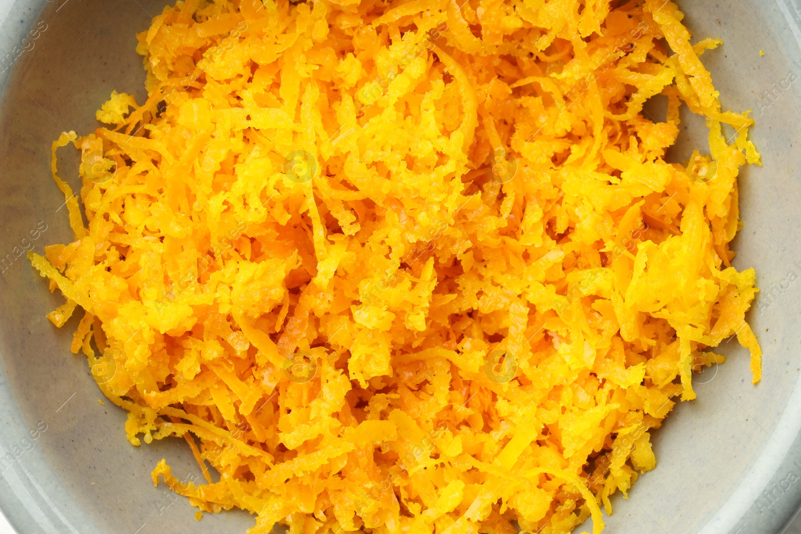 Photo of Fresh orange zest in bowl, top view