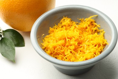 Photo of Fresh orange zest in bowl on light table, closeup