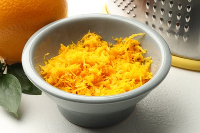 Photo of Fresh orange zest in bowl on light table, closeup