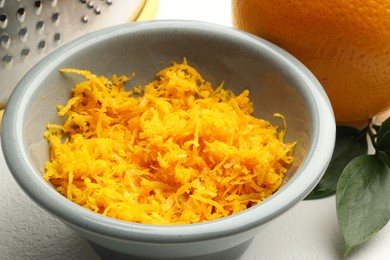 Photo of Fresh orange zest in bowl on light table, closeup