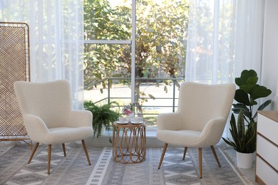 Stylish living room interior with soft white armchairs