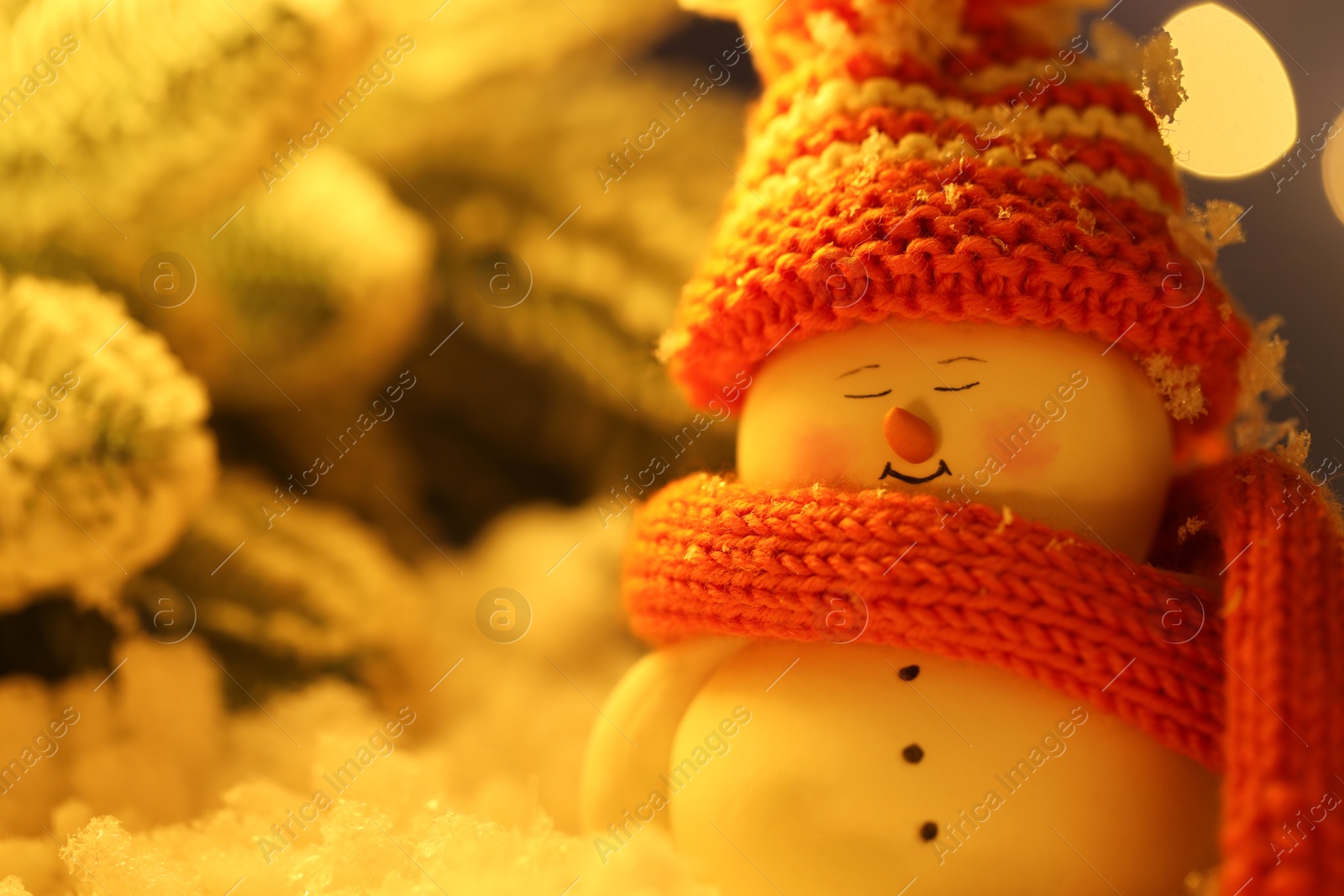 Photo of Cute decorative snowman on artificial snow against blurred background, closeup