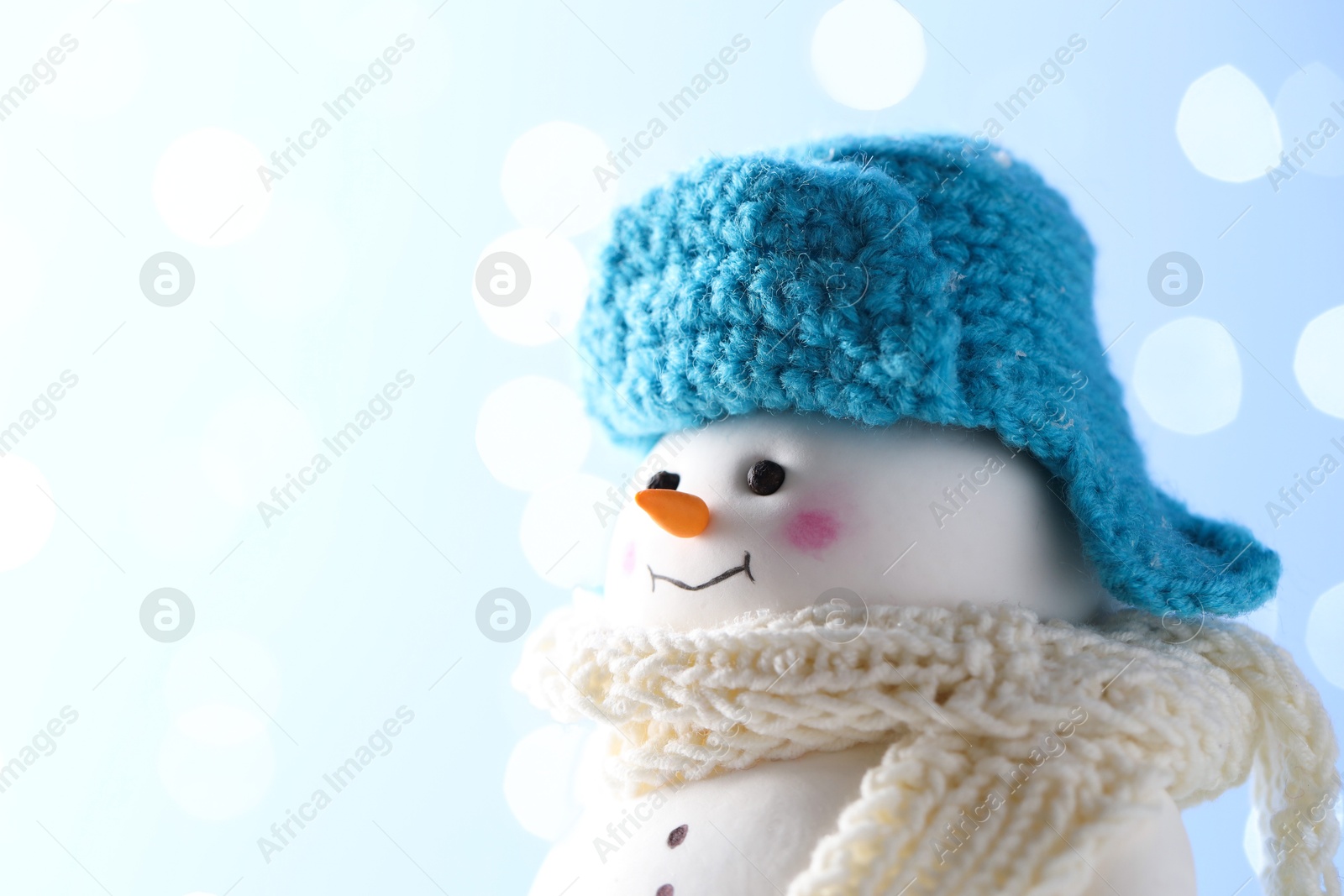 Photo of Cute decorative snowman against light blue background, closeup. Space for text