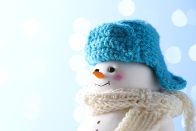 Photo of Cute decorative snowman against light blue background, closeup. Space for text