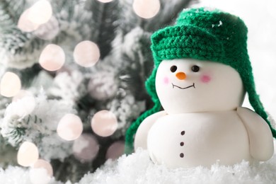 Photo of Cute decorative snowman and fir tree branches on artificial snow against white background, closeup