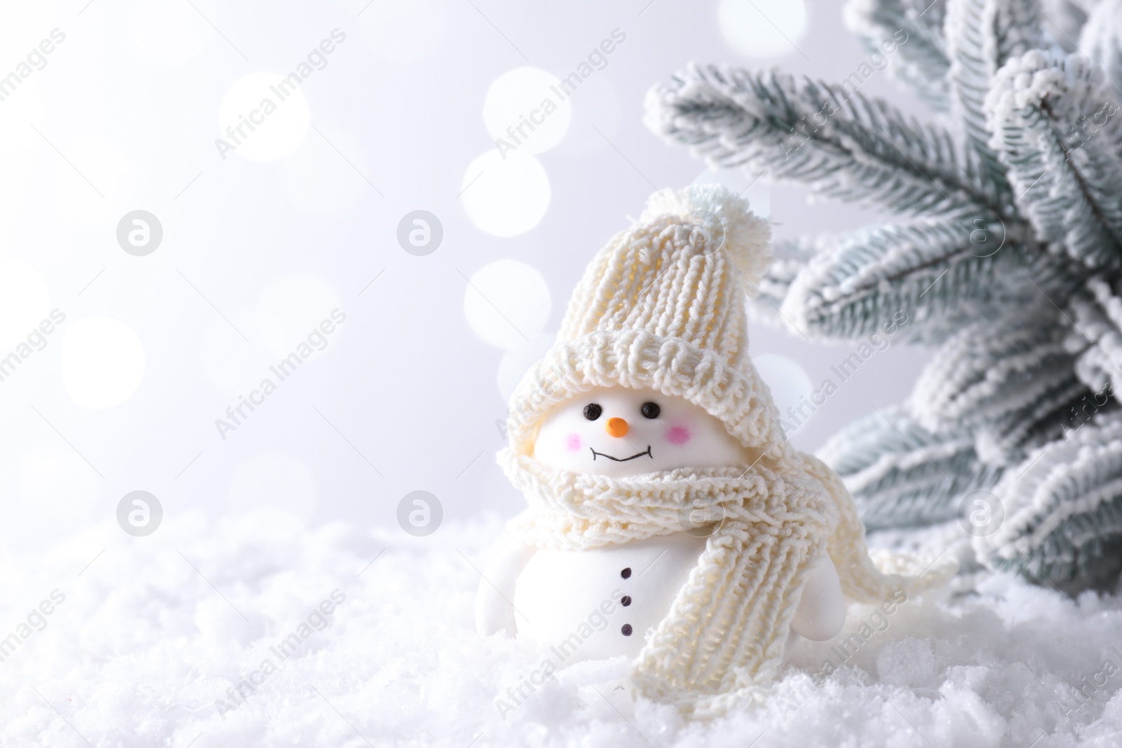 Photo of Cute decorative snowman on artificial snow against light background, space for text