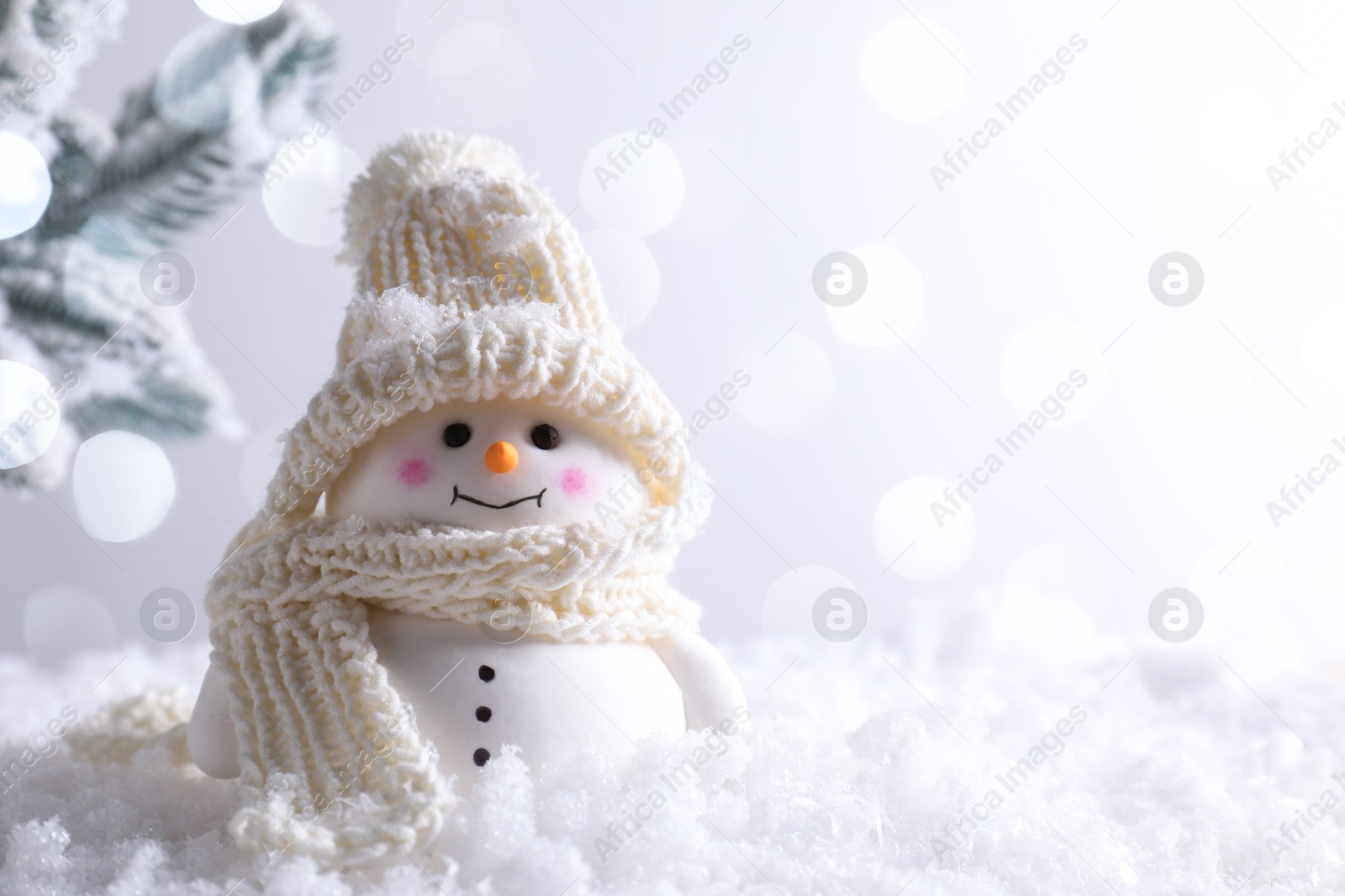 Photo of Cute decorative snowman on artificial snow against light background, space for text