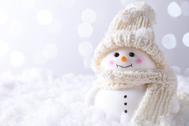 Photo of Cute decorative snowman on artificial snow against light background, closeup. Space for text