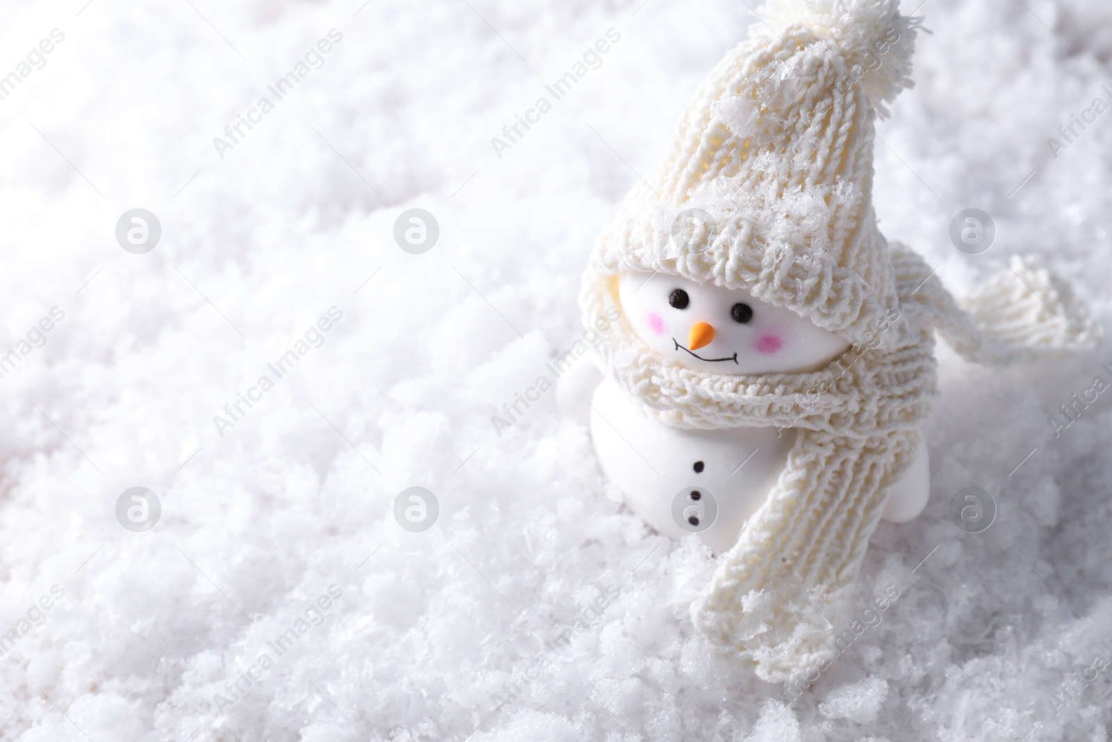 Photo of Cute decorative snowman on artificial snow, above view. Space for text