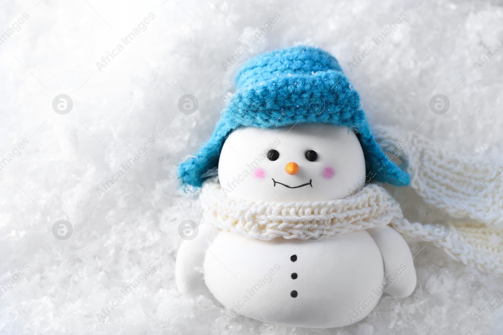 Photo of Cute decorative snowman on artificial snow, top view