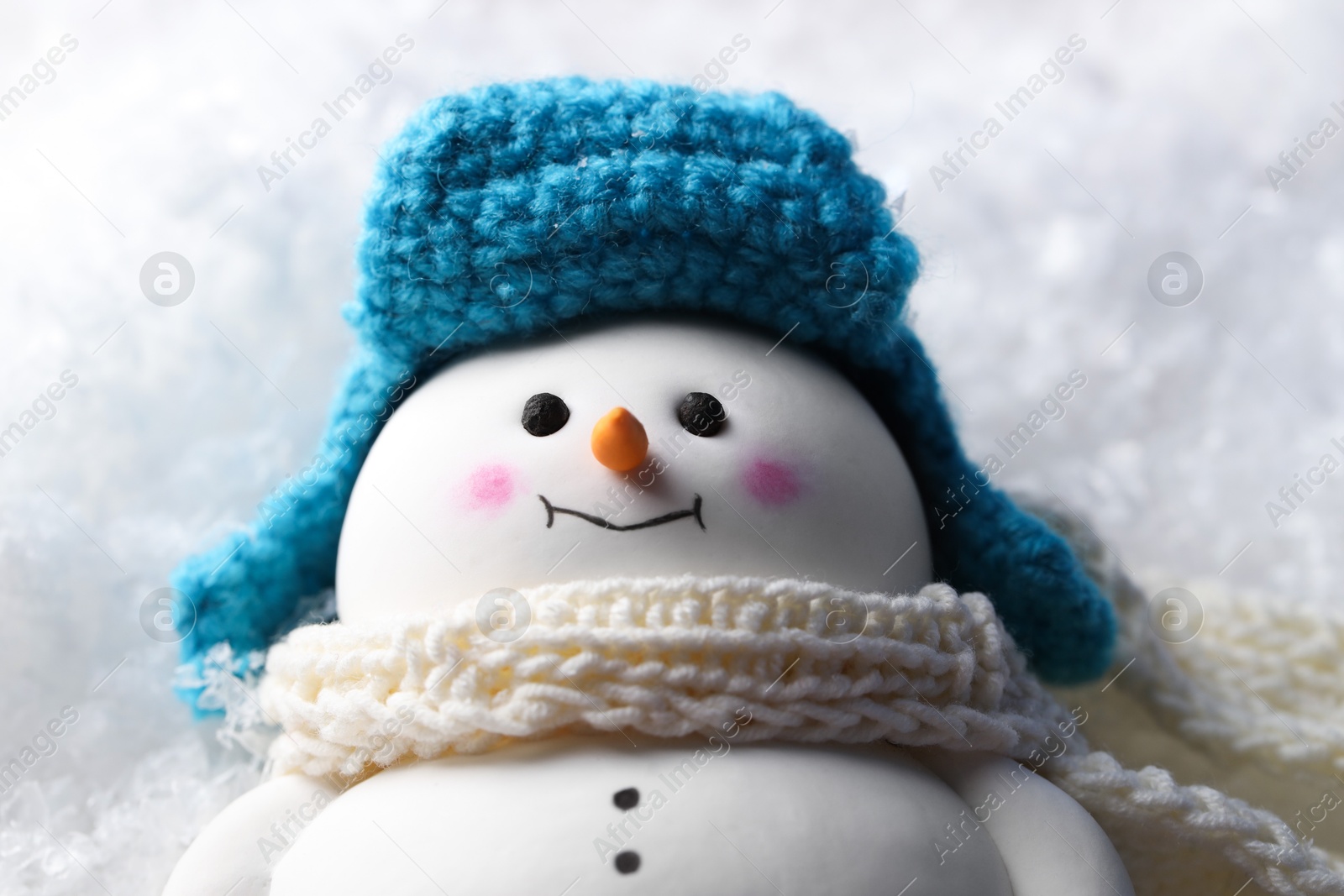 Photo of Cute decorative snowman on artificial snow, closeup