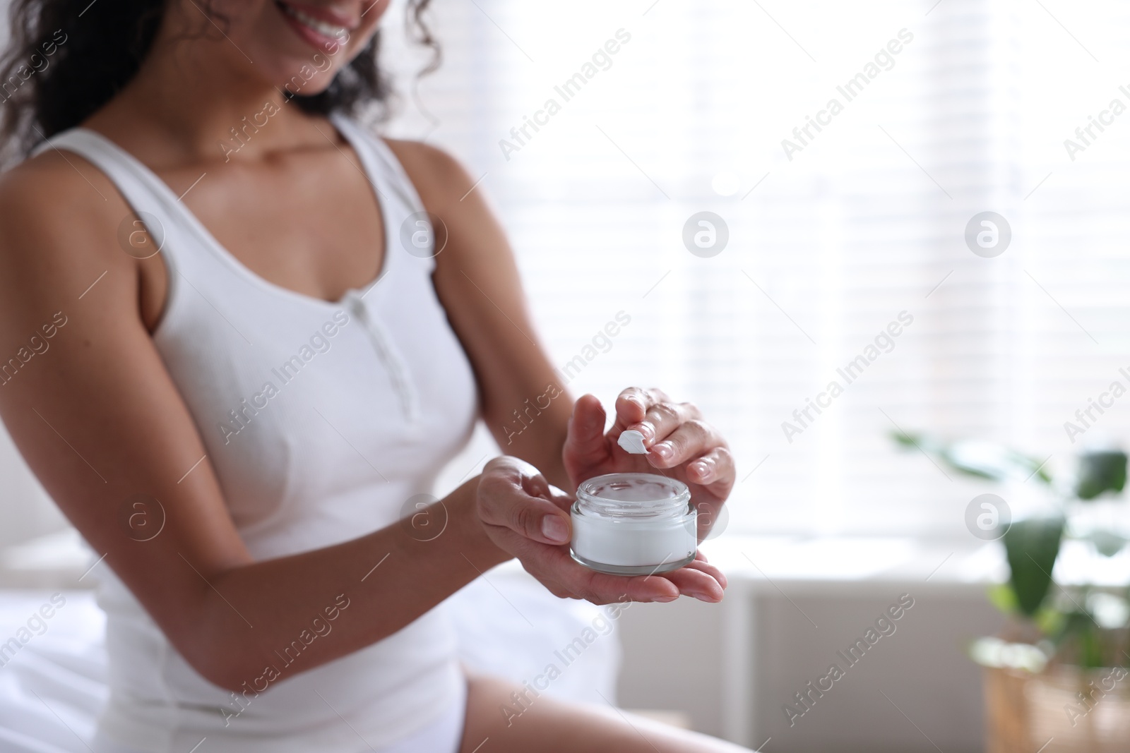 Photo of Woman with jar of cream at home, closeup. Space for text