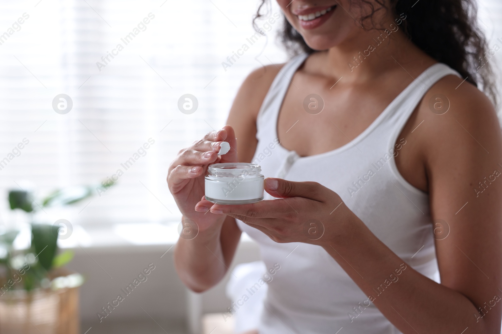 Photo of Woman with jar of cream at home, closeup. Space for text