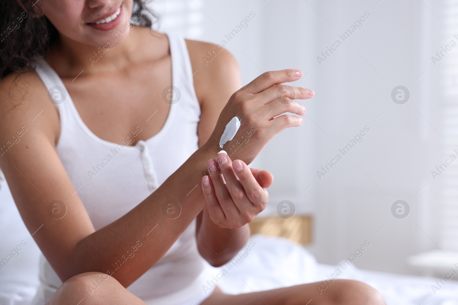 Photo of Woman applying cream onto hand at home, closeup. Space for text