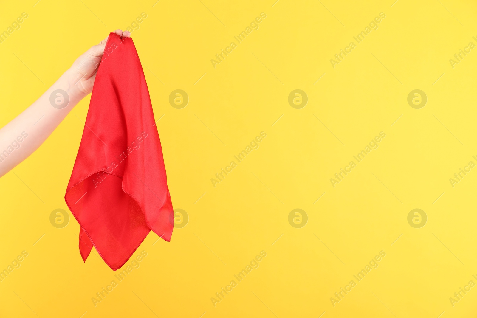 Photo of Woman holding red handkerchief on yellow background, closeup. Space for text