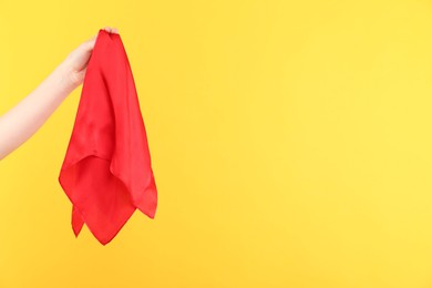 Photo of Woman holding red handkerchief on yellow background, closeup. Space for text