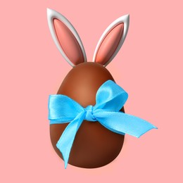 Happy Easter. Chocolate egg with bunny ears and light blue bow on pink background